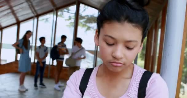 Школьные друзья издеваются над грустной девушкой в коридоре — стоковое видео