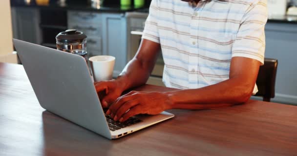 Senior man using laptop while having coffee — Stock Video