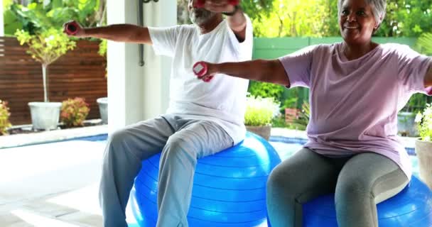 Старшая пара занимается спортом с гантелями дома — стоковое видео