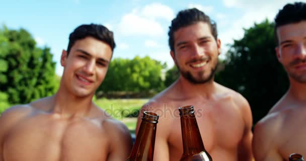 Group of male friends toasting beer bottles at poolside — Stock Video