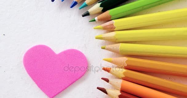 Colored pencils arranged in semi circle with heart on white background — Stock Video