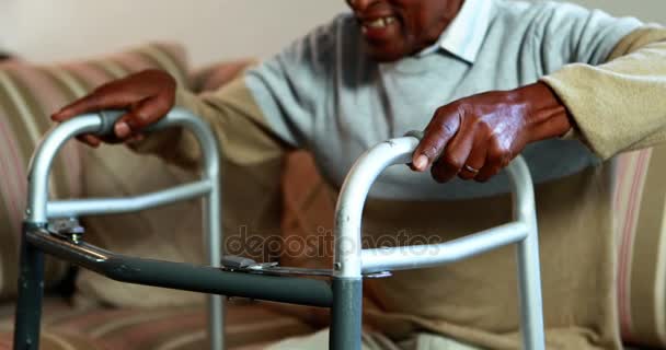 Senior mannen reser sig upp från soffan med walker — Stockvideo