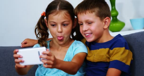 Siblings taking selfie from mobile phone in living room — Stock Video