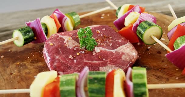 Marinated steak and skewered vegetables on wooden board — Stock Video