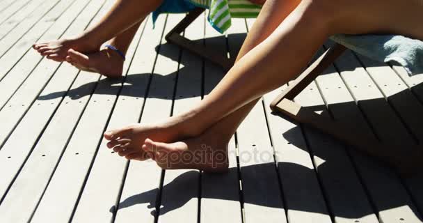Duas mulheres deitadas em cadeiras de praia tomando banho de sol — Vídeo de Stock