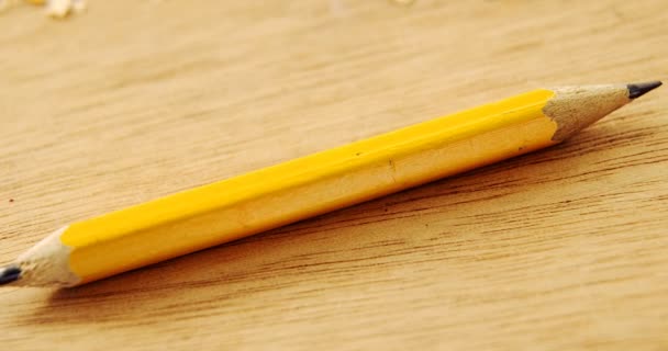 Broken yellow pencil and sharpener on wooden background — Stock Video