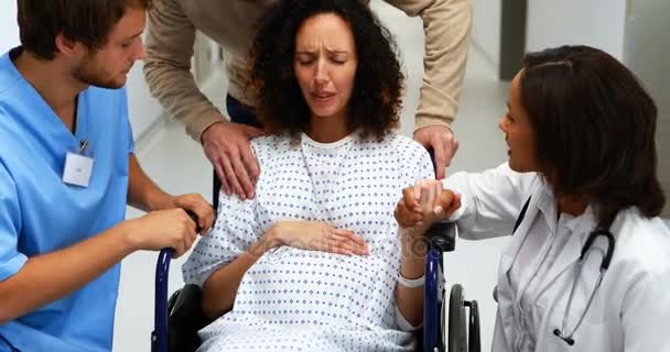 Ärzte und Mann trösten Schwangere auf Flur — Stockvideo