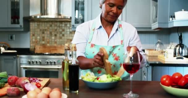 Pareja mayor preparando ensalada en la cocina — Vídeos de Stock