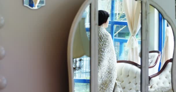 Mujer mirando por la ventana en la sala de estar — Vídeo de stock