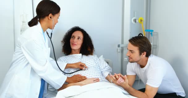 Doctor examining pregnant woman with stethoscope in ward — Stock Video