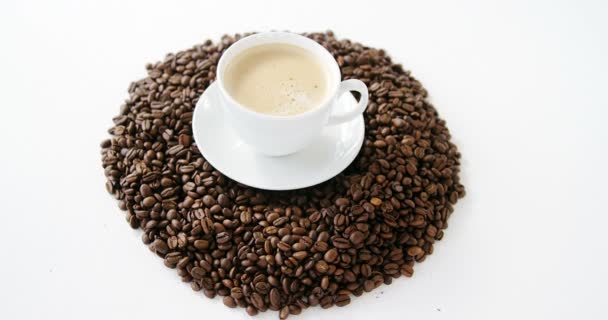 Чашка кави в оточенні смажених бобів — стокове відео