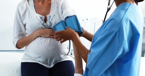 Sección media del médico que revisa la presión arterial de la mujer embarazada — Vídeos de Stock