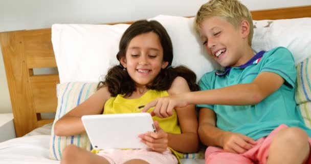 Братья и сестры с помощью цифрового планшета в спальне — стоковое видео