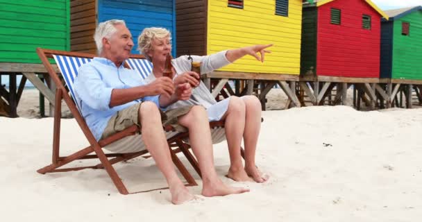 Idősebb pár pirítás ital színes strand kunyhó közelében — Stock videók
