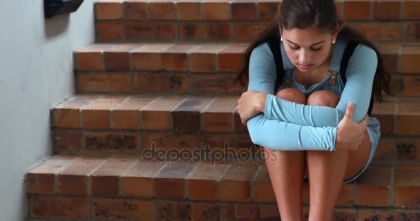 Trauriges Schulmädchen sitzt allein auf Treppe — Stockvideo