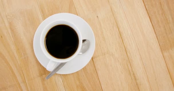 Café negro servido en taza blanca sobre tabla de madera — Vídeo de stock