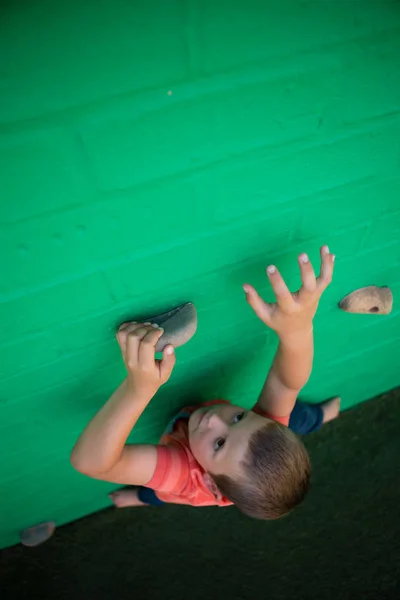 Pojken klättrar på grön vägg — Stockfoto