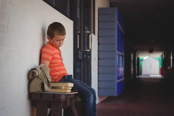 Niño sentado en el banco por la pared —  Fotos de Stock