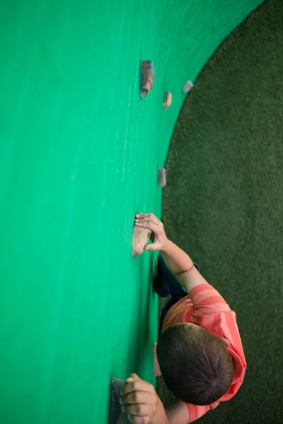 小男孩在绿色的墙上爬 — 图库照片