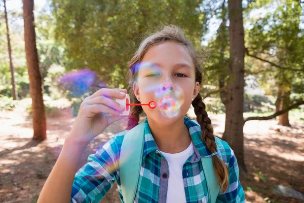 Flicka som blåser bubblor i skogen — Stockfoto