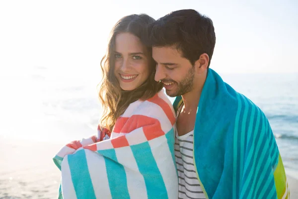 Пара завернутая в одеяло на пляже — стоковое фото