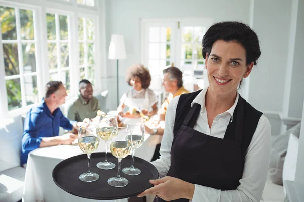 Улыбающаяся официантка с бокалами вина в подносе — стоковое фото