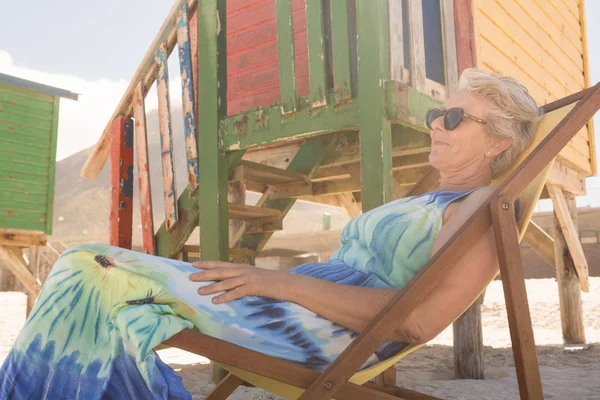 Пожилая женщина в солнечных очках отдыхает на стуле — стоковое фото
