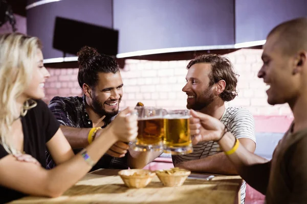 Friends toasting beer mugs at nightclub — Stock Photo, Image