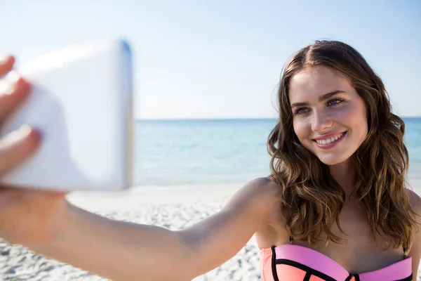 Donna che indossa bikini mentre prende selfie in spiaggia — Foto Stock