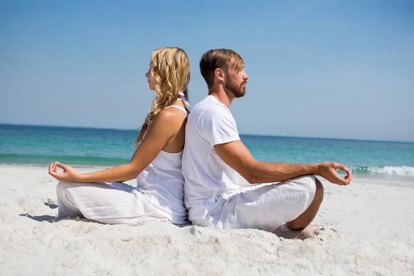 Vista lateral do casal meditando na praia — Fotografia de Stock