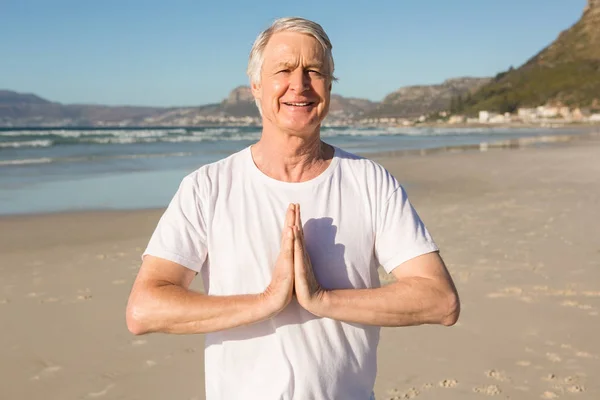 Homem sênior fazendo ioga na praia — Fotografia de Stock