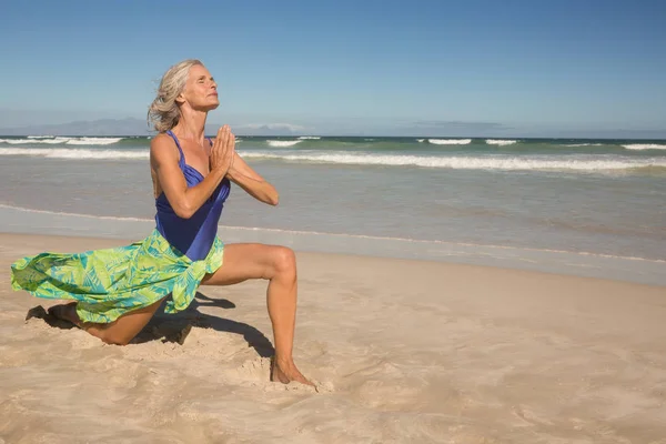 Ανώτερος γυναίκα άσκηση γιόγκα στην άμμο — Φωτογραφία Αρχείου