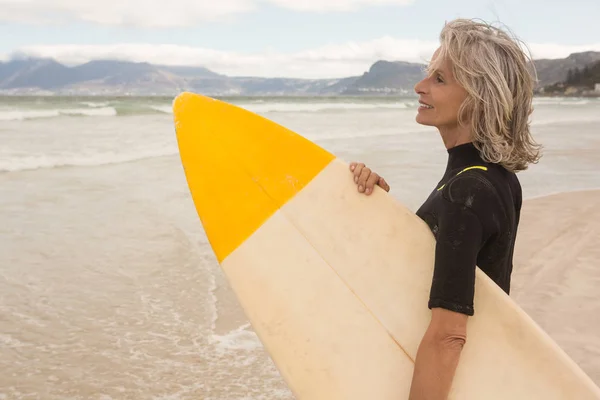 Vrouw met surfplank terwijl staande op de oever — Stockfoto