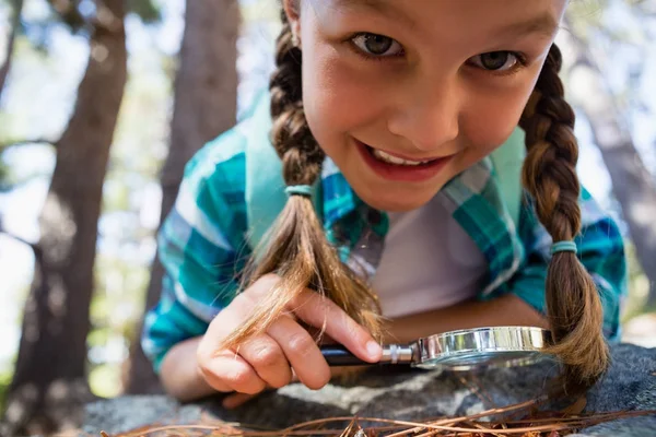 Girl using magnifying glass in forest — Stock Photo, Image