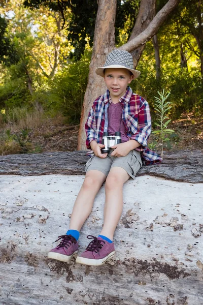 Pojken sitter på fallna trädstam — Stockfoto