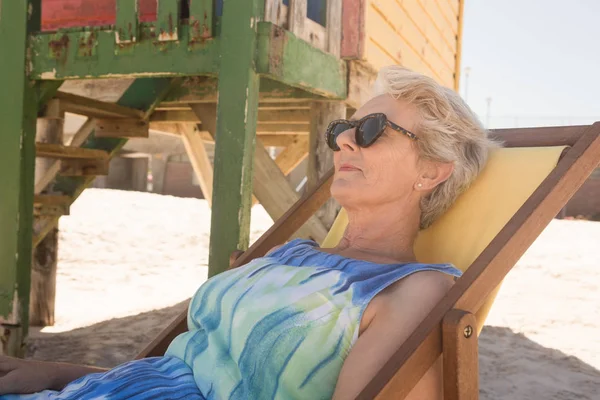 Femme âgée avec des lunettes de soleil reposant sur la chaise — Photo
