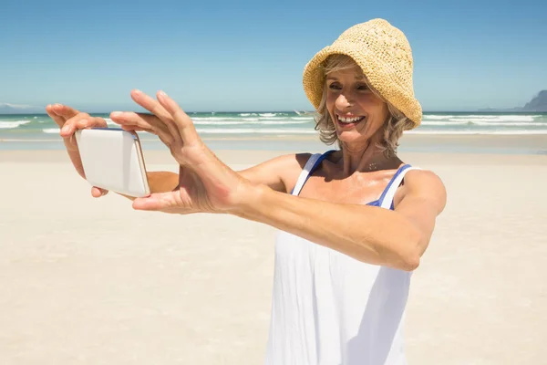 Жінка використовує смартфон на пляжі — стокове фото