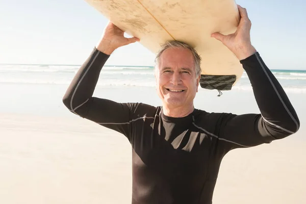 Usmíval se starší muž nesoucí surfovací prkno — Stock fotografie
