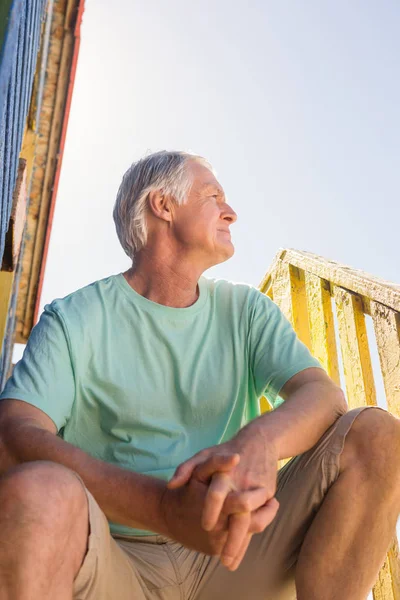 Senior man looking away while sitting at hut — Stock Photo, Image