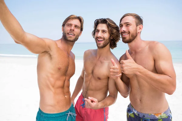 Smiling male friends standing at beach — Stock Photo, Image