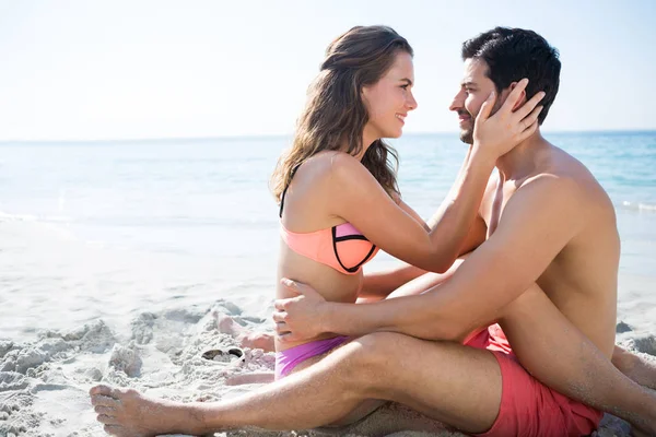 Пара сидит лицом к лицу на песке на пляже — стоковое фото