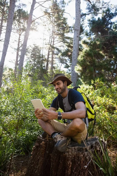 Ağaç kütüğü üzerinde dinlenme tablet kullanan adam — Stok fotoğraf