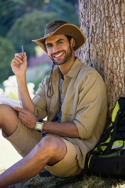 Homem com bloco de notas e caneta descansando perto da árvore — Fotografia de Stock