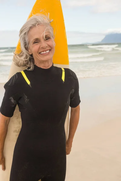 Весела жінка, що стоїть з дошкою для серфінгу — стокове фото