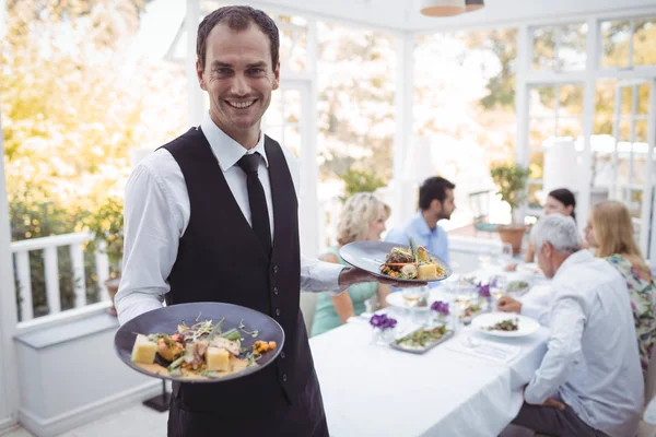 Camarero sonriente sosteniendo bandeja de comida —  Fotos de Stock