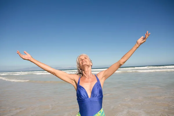 Senior Kvinna med armarna utsträckta på stranden — Stockfoto