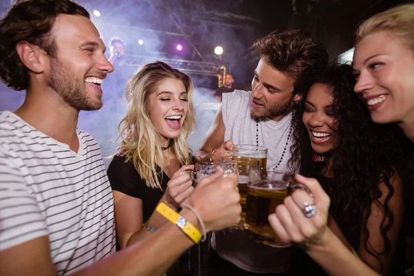 Vrienden roosteren bierpullen in nachtclub — Stockfoto