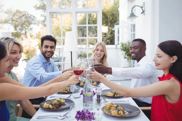Friends toasting glasses of wine during meal — Stock Photo, Image