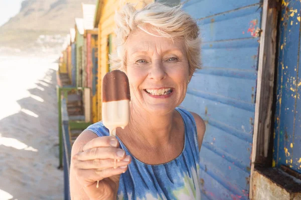 Mulher sênior segurando sorvete enquanto por cabana — Fotografia de Stock