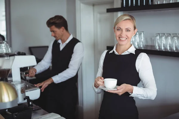 Waitress holding cup of coffee at counter — Stock Photo, Image